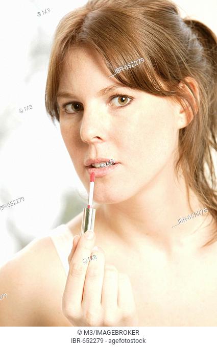 Smiling young woman applying lipp gloss