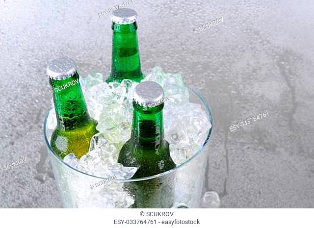 Three green beer bottles in a crystal ice bucket. High angle with copy space to the right side. Horizontal format