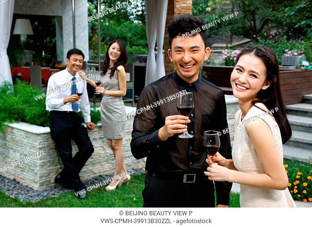 Young people holding glasses of red wine outside