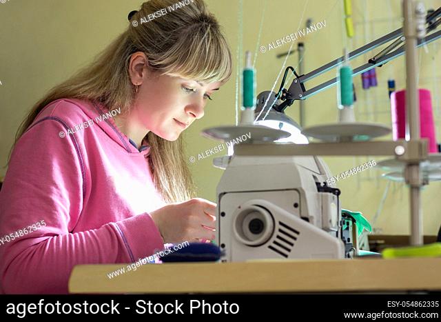 Girl happily sews on a professional sewing machine