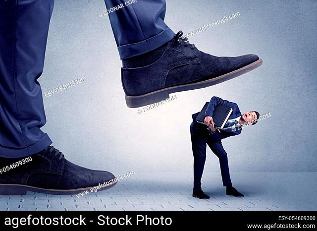 Young handsome businessman getting crushed by a big formal shoe