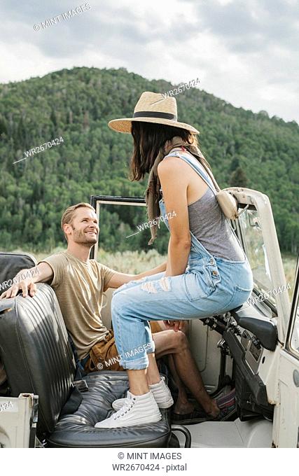 A couple on a road trip sitting in an open topped jeep