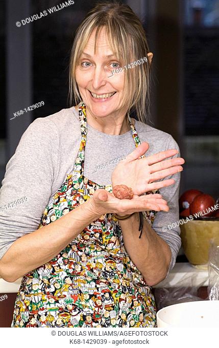 a woman, 56, prepares meat ball in her kitchen
