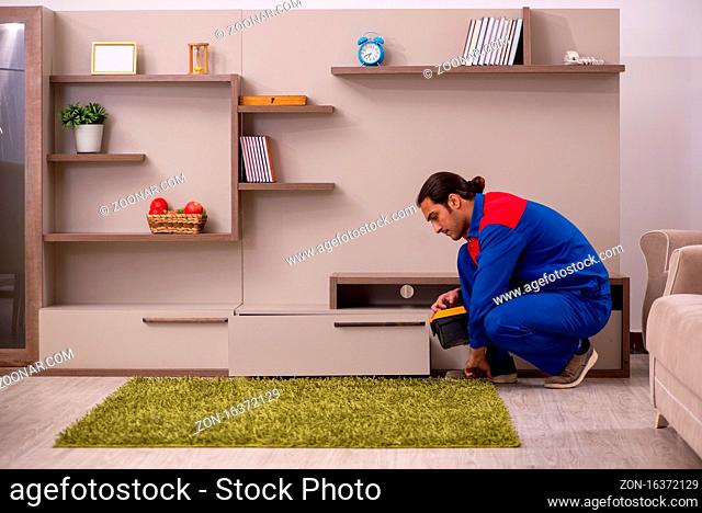 Young contractor repairing drawyer indoors