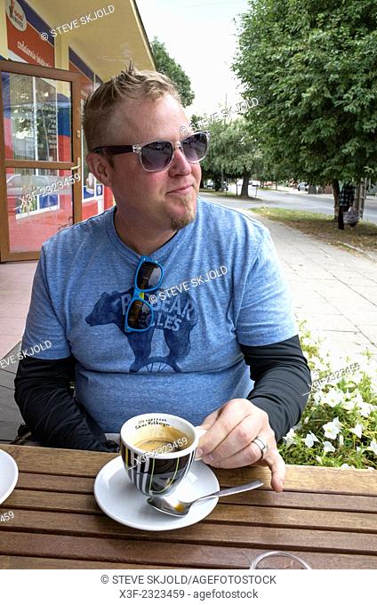 American man living in Poland enjoying his espresso at a sidewalk cafe. Rawa Mazowiecka Central Poland
