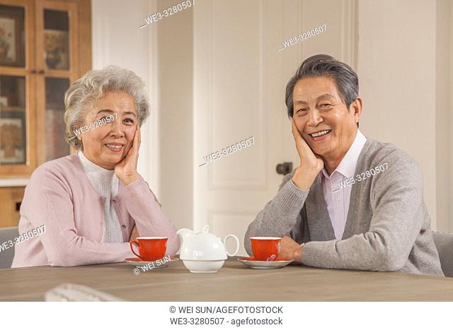 Happy old couple drinking tea in the kitchen, Chinese ethnicity