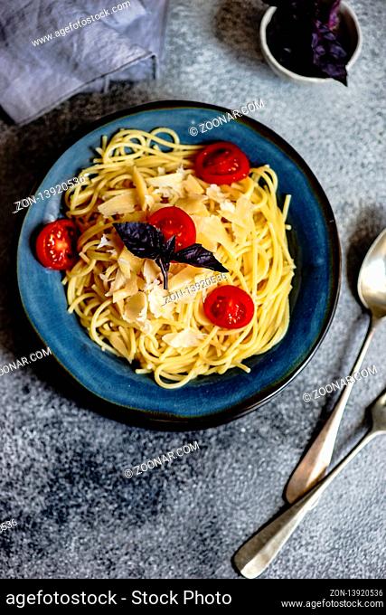 Italian pasta with cherry tomatoes and basil in a ceramic bowl on stone background with copy space