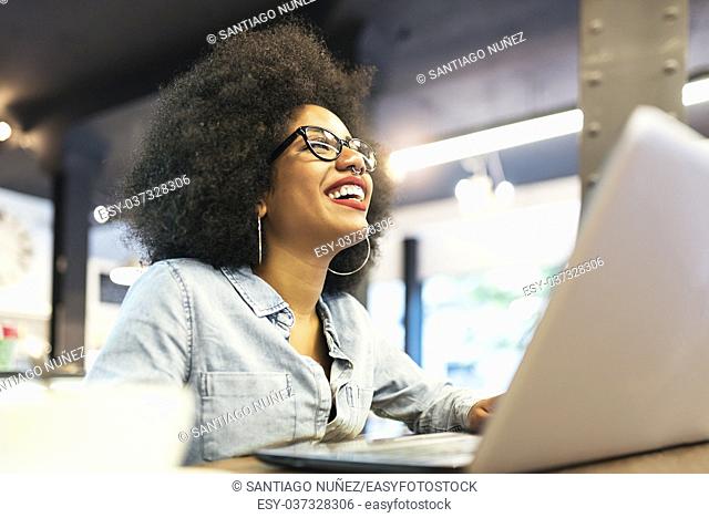 Beautiful afro american woman using mobile and laptop in the coffee shop. Communication concept