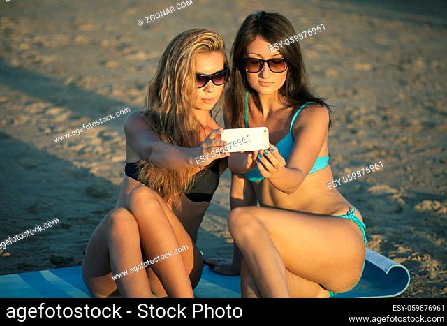 Beautiful girls in bikinis on the beach doing selfie