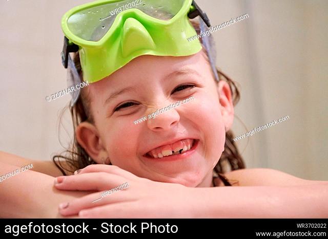 little girl with snorkel goggles in the tub while taking a bath in the bathtub, kids hygiene concept and summer vacation in corona virus stay at home