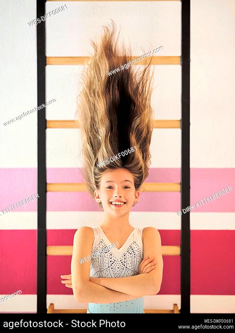 Smiling girl with arms crossed hanging on wall bars