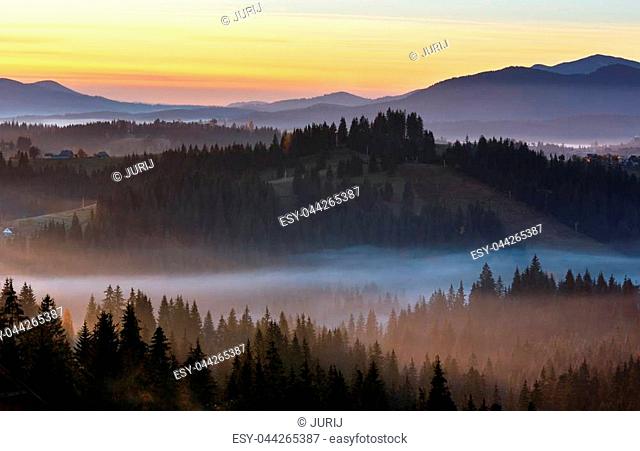 Early morning fog over the autumn slopes of Carpathian Mountains (Yablunytsia village and pass, Ivano-Frankivsk oblast, Ukraine)