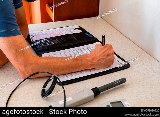A professional building inspector is viewed closeup, filling out forms during an inspection of a residential dwelling, with room for copy