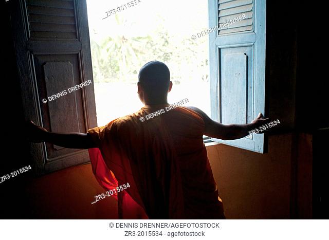 A monk opens a window in a small village temple outside of Phnom Penh, Cambodia