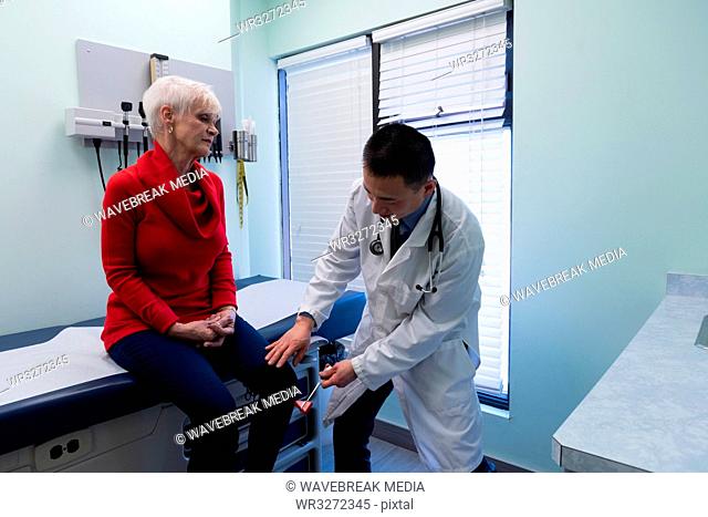 Young Asian male doctor examining a senior patient with reflex hammer