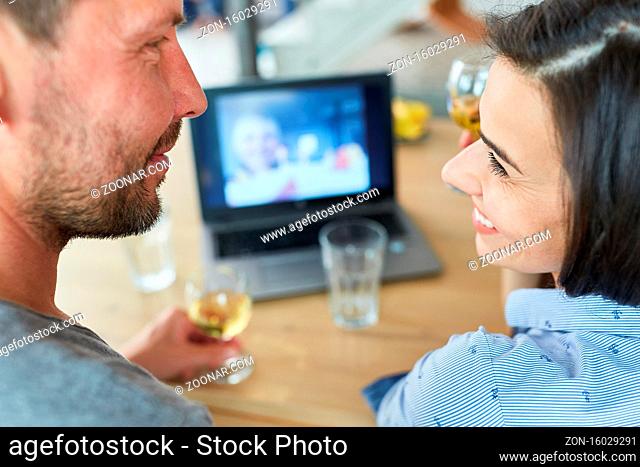Glückliches Paar im Videochat am Laptop Computer trinkt Wein und feiert online