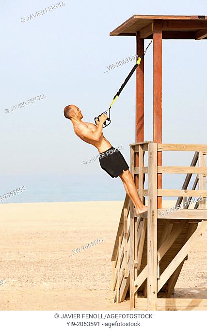man playing sports on the beach with trx