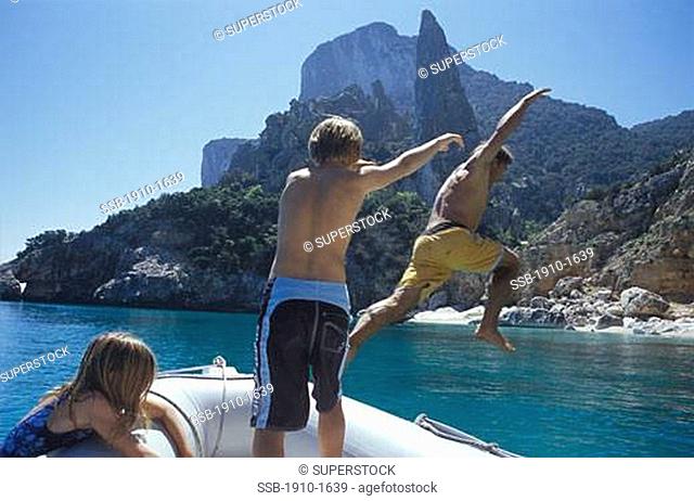 Boy 12 pushing father off boat while daughter looks on near Cala Ganone Sardinia This area is part of the Gulf of Orosei a Marine oasis inside the Gennargentu...