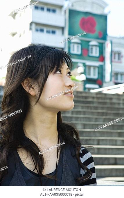 Young woman outdoors, looking up, stairs in background