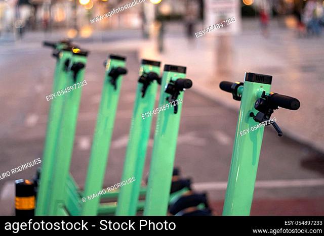 Green electric scooters for rent parked on the city