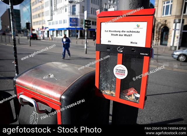 17 April 2020, Hamburg: A so-called ""ballot bin"" for cigarette butts with the question ""Is Hamburg the most beautiful city in the world"" hangs next to a...