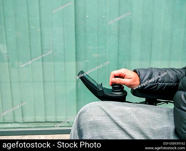 Close up of a disabled person hand driving electric wheelchair using joystick