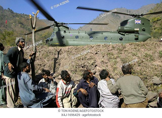 Helicopter with relief goods lands in a village Due to the wind of the rotors villagers have to find protection as stones are flying around Saidpur, Kashmir