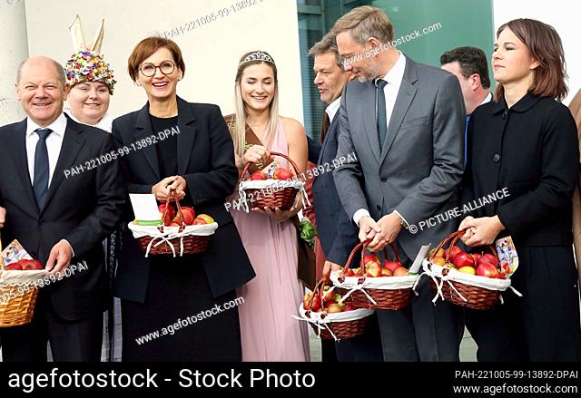 05 October 2022, Berlin: Chancellor Olaf Scholz (SPD, l) and members of the federal government are presented with baskets full of apples before the cabinet...