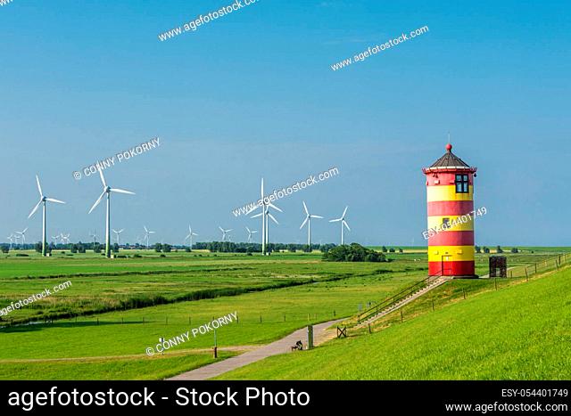 The famous Pilsum Lighthouse with wind turbines in the background near the East Frisian village of Greetsiel on the German North Sea coast of Lower Saxony