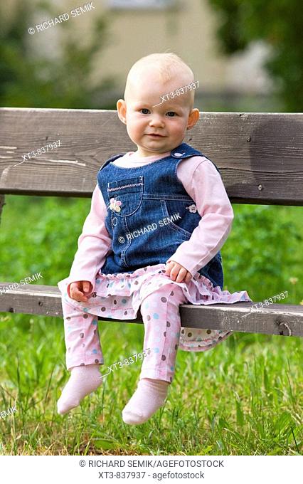 11 months old baby girl sitting on a bench