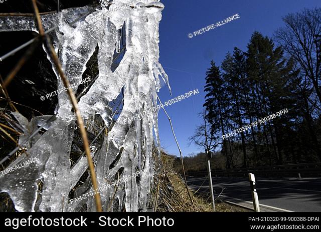 20 March 2021, North Rhine-Westphalia, Monschau: Ice hangs from a wire netting used to secure a federal highway. During the night