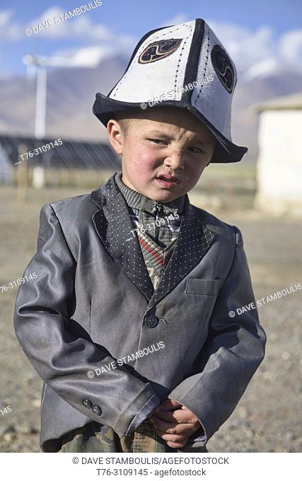 Scowling Kyrgyz boy in traditional kalpak hat, Karakul Lake, Tajikistan