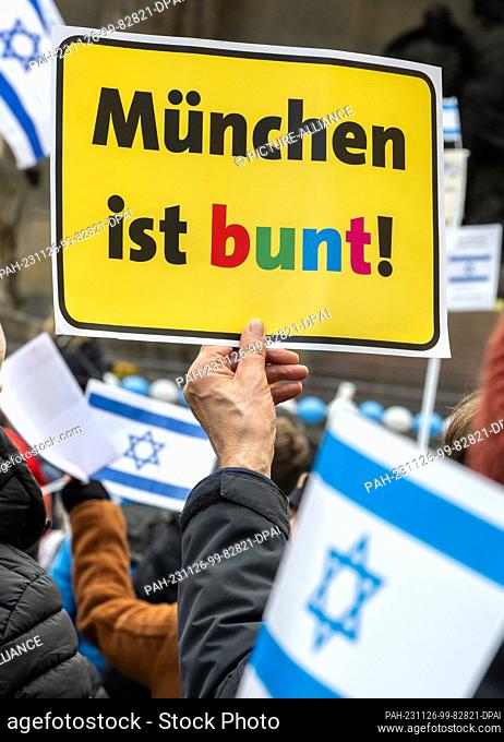 26 November 2023, Bavaria, Munich: At a rally for Israel on Odeonsplatz, a participant holds a sign reading ""IMünchen ist bunt!"" (Munich is colorful