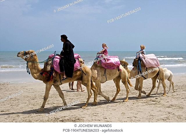 Tunesia, Djerba, Midoun, children enjoying a camel ride on the beach