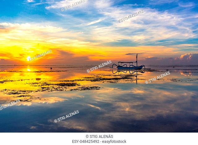 An indonesian fishing boat at sunrise, reflections in the water, Sanur, Bali, Indonesia, April 21, 2018