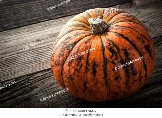 Orange pumpkin with green stripes on the wooden table horizontal