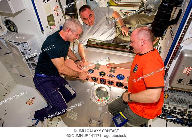 In the Unity node, NASA astronaut Steve Swanson (left), Expedition 40 commander, adds the Expedition 40 patch to the growing collection of insignias...
