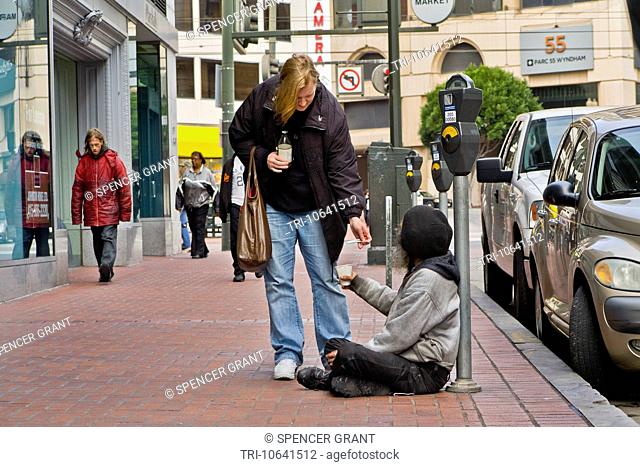 A charitable woman gives cigarettes to a homeless panhandler just off Market Street in San Francisco