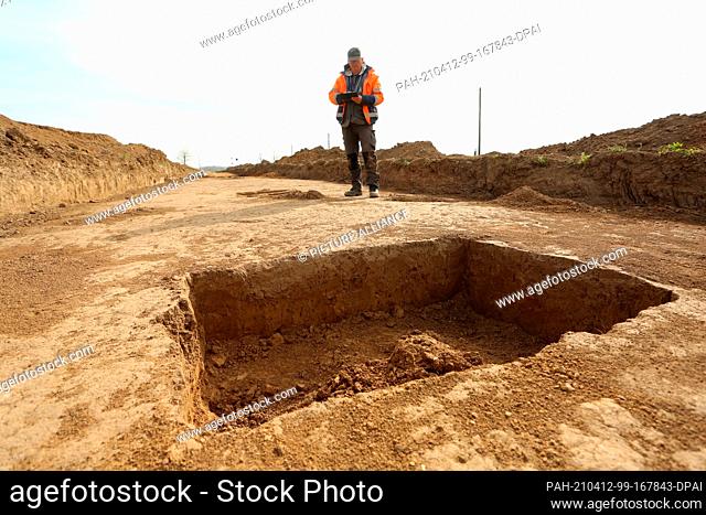09 April 2021, Saxony-Anhalt, Derenburg: Excavation director Christian Rauh maps an uncovered grave during archaeological investigations at a construction site...