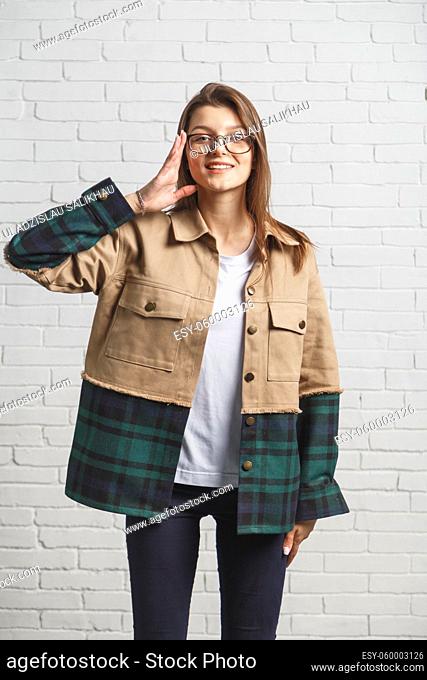 Portrait of young hipster woman in eyeglasses over white brick wall. Eyesight consept
