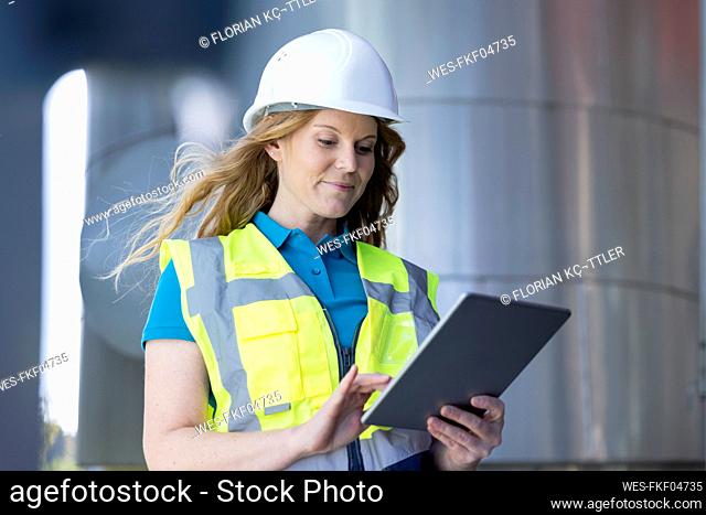 Technician using tablet PC standing in industry
