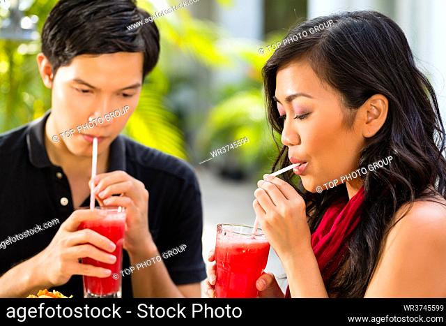Asian man and woman in restaurant are drinking Cocktails