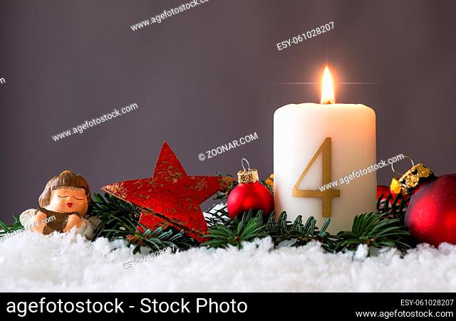 Candle of the fourth Advent burns, fir branches and Christmas tree balls in the snow, seasonal or holidays concept