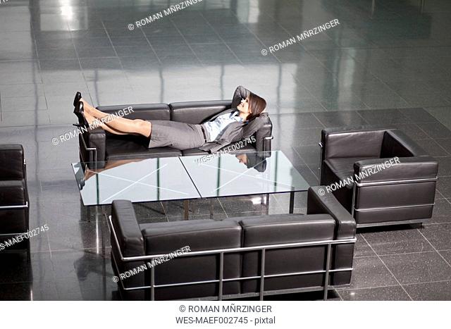Germany, Bavaria, Business woman resting on sofa
