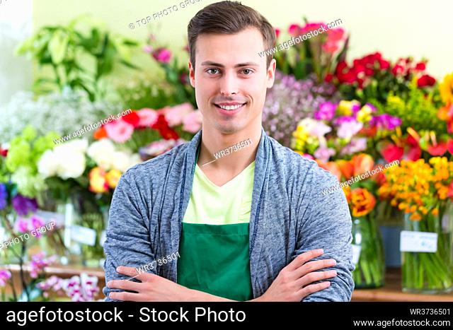Young handsome florist selling flowers and bouquets in shop