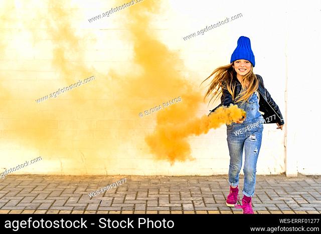 Portrait of smiling girl with orange smoke torch