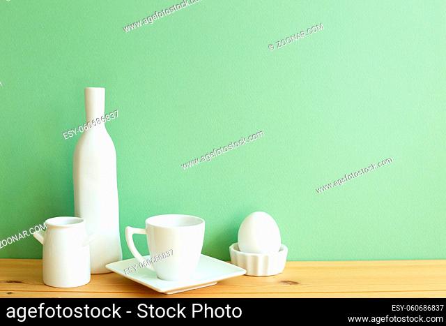 White ceramic dishware on wooden table. green background