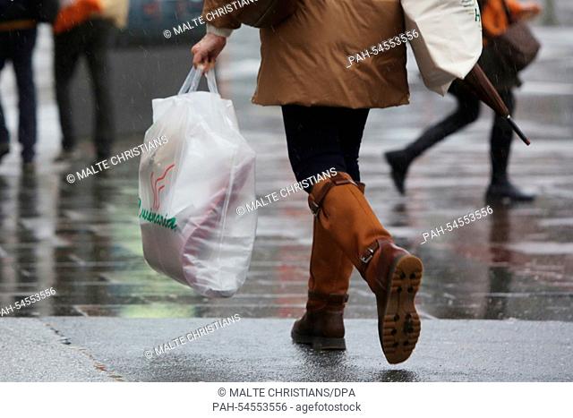 A woman carrying a bag of Christmas shopping items walks through the rain in Hamburg, Germany, 22 December 2014. Shortly before Christmas the weather is rainy...