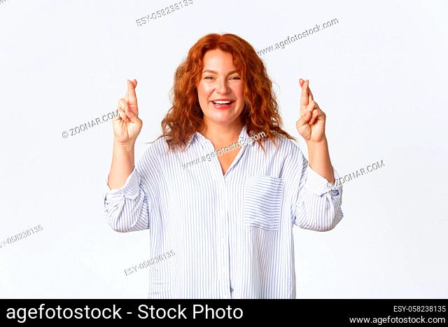 Hopeful optimistic redhead woman keep faith dreams do come true, smiling upbeat, cross fingers good luck and awaiting for fortune, positive news