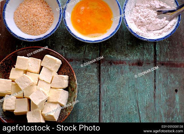 Frugal vegetarian food from Vietnamese cuisine, fried tofu with spice power, cover with crispy flour, raw material for homemade food on wooden background